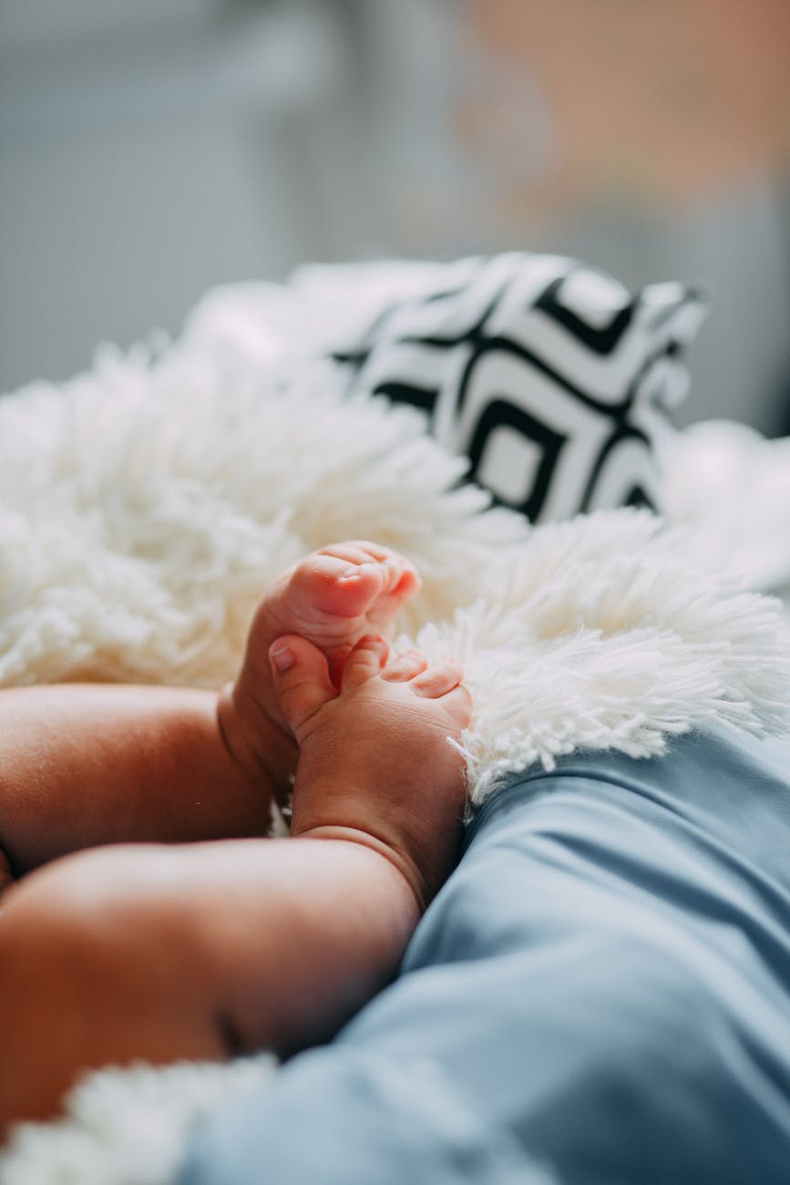 baby in blue shorts lying on white fur textile